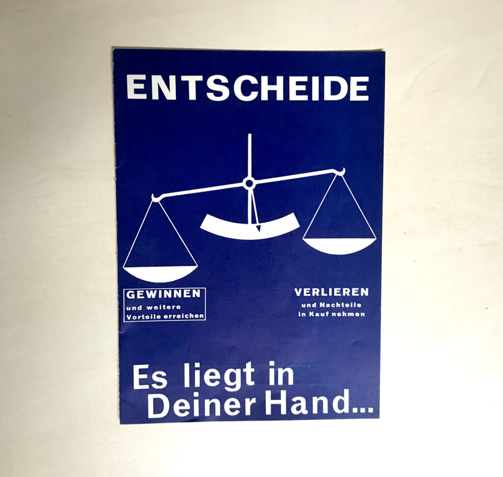 Ein altes Werbeprospekt des KOV in dunkelblau mit weißer Schrift und einer weißen Waage. Ganz oben steht "Entscheide", bei der tieferen Waagschale steht "Gewinnen und weitere Vorteile erreichen" bei der tieferen Waagschale steht "Verlieren und Nachteile in Kauf nehmen", ganz unten heißt es "Es liegt in Deiner Hand ..."